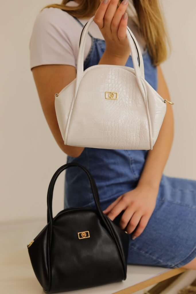 Elegant black and white handbags displayed in a modern studio setting with a model.