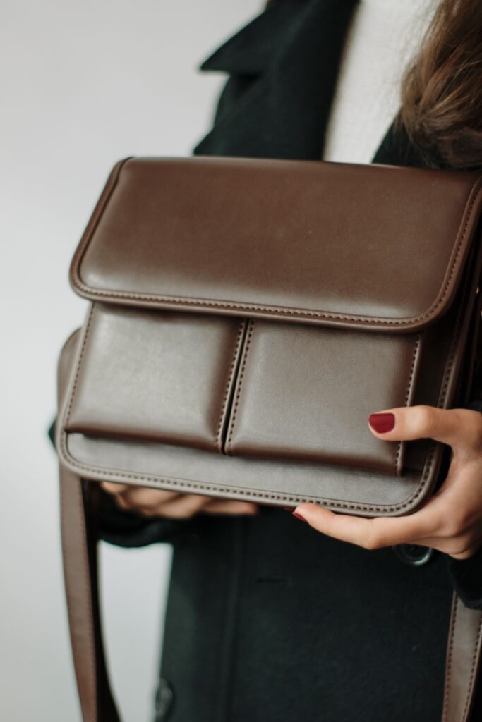 Close-up of a woman holding an elegant brown leather handbag, showcasing fashion and elegance.