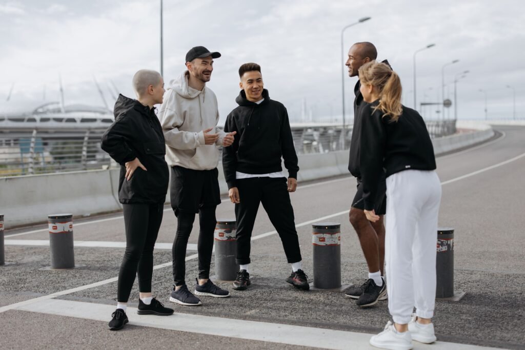 Five adults in activewear chatting on an urban street during the day.