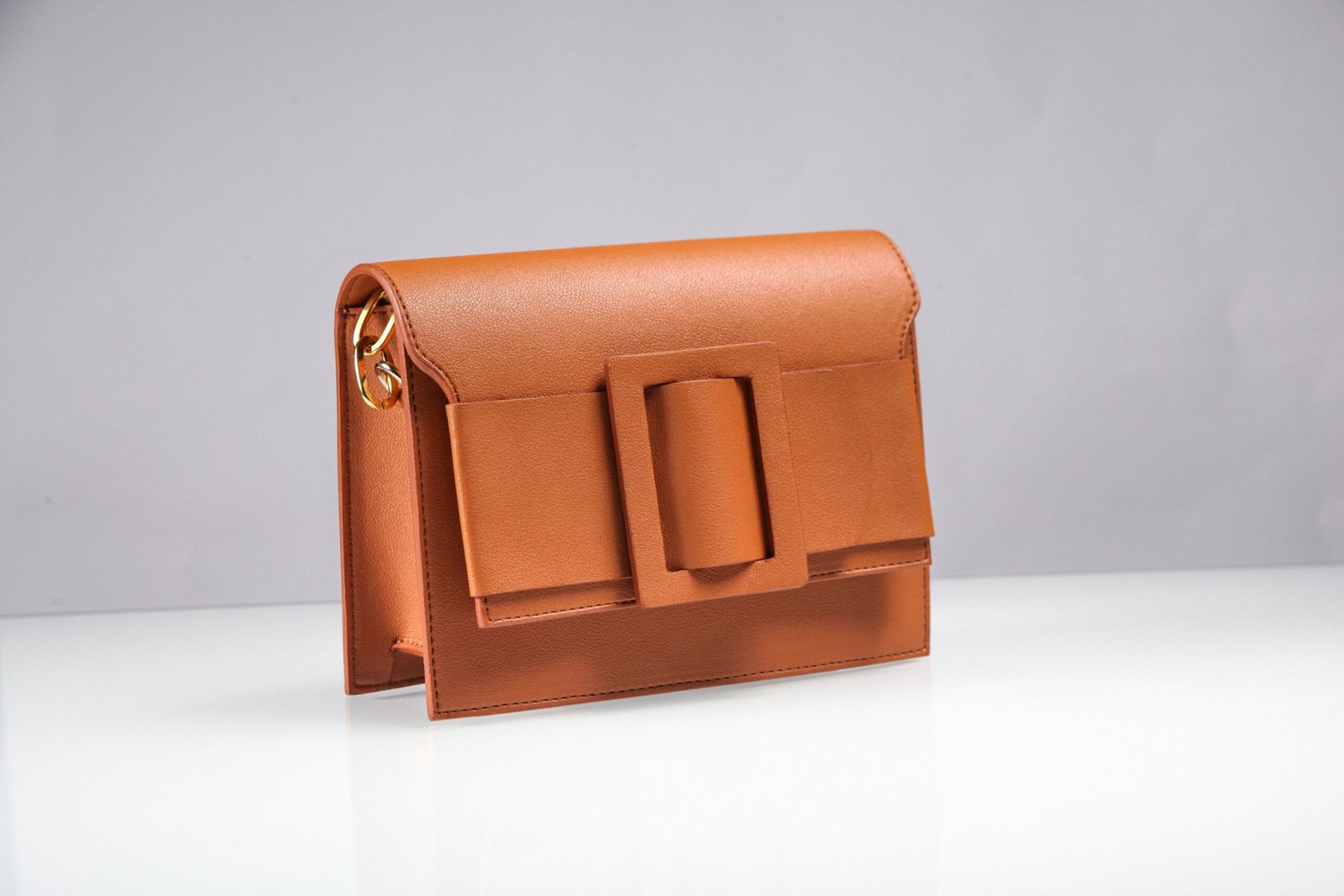 Elegant brown leather handbag displayed on clean white surface, showcasing fashion style.